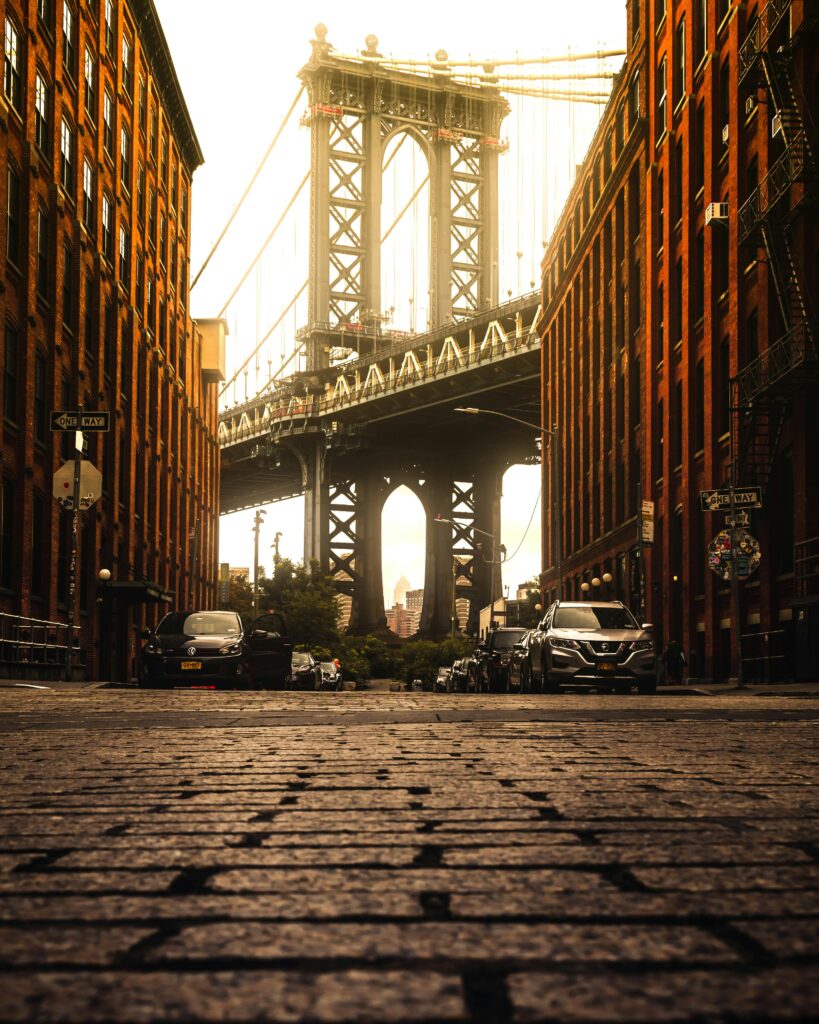 Captured in Dumbo, Brooklyn, this view highlights the iconic Brooklyn Bridge framed by urban architecture at sunset.