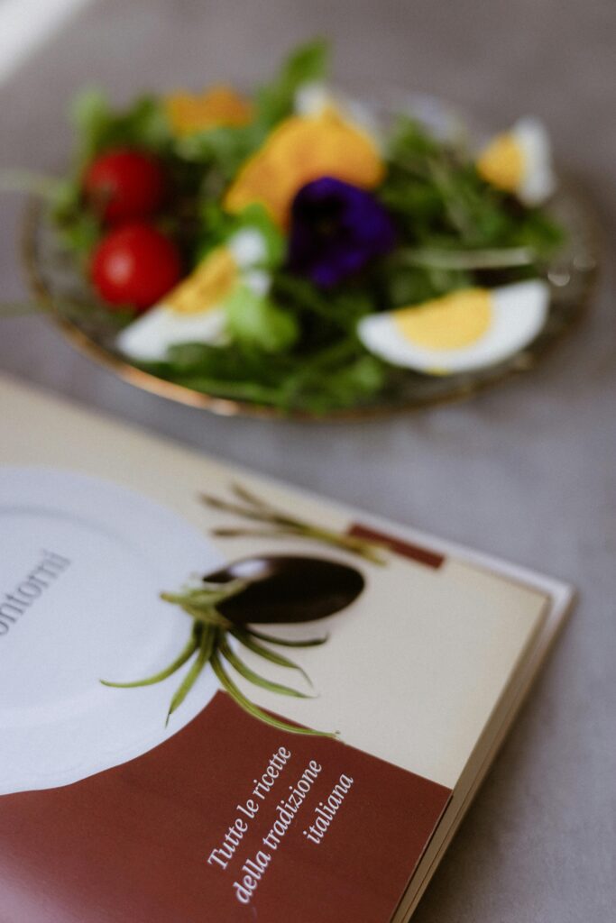 Plate with salad and Italian cookbook on a table, emphasis on healthy eating and culinary inspiration.