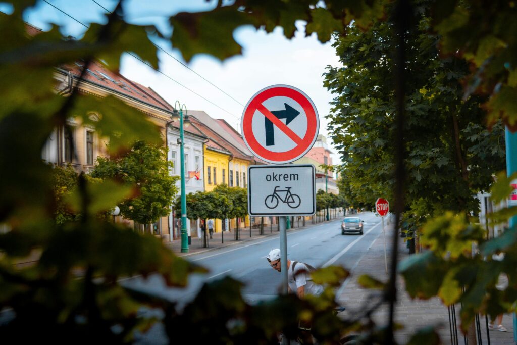 Urban street view featuring a no right turn sign and cyclist in a leafy European city.