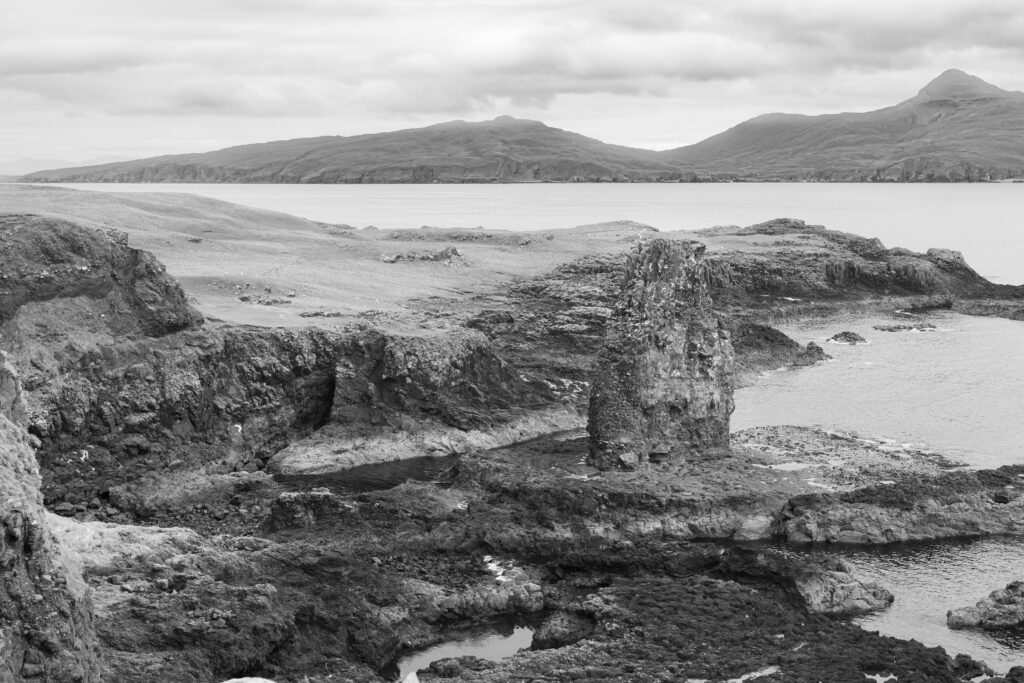 A dramatic black and white landscape showcasing the rugged coast of Isle of Canna, Scotland.
