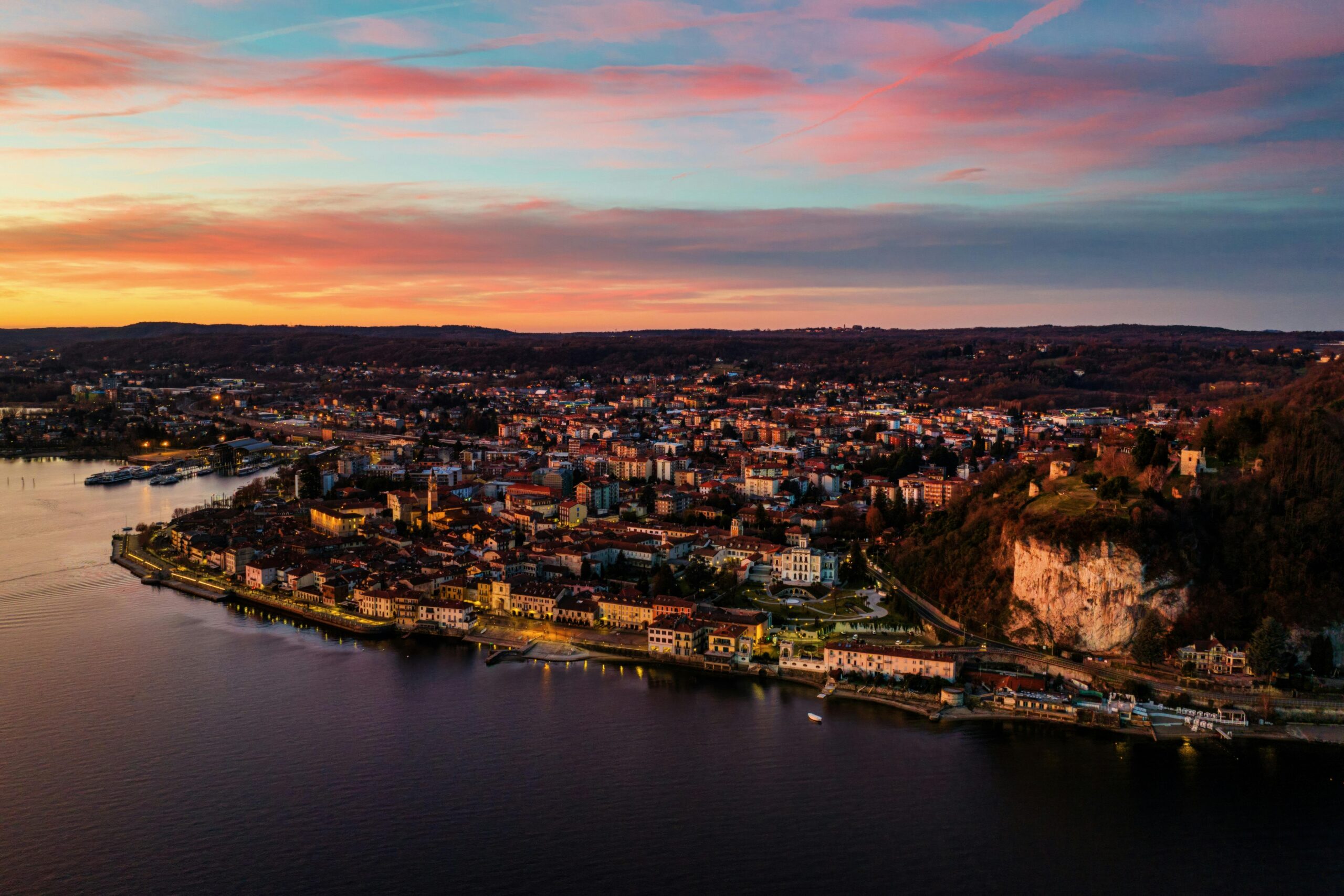 Breathtaking aerial view of Lake Maggiore at sunset in Arona, Italy with vivid colors and historic architecture.
