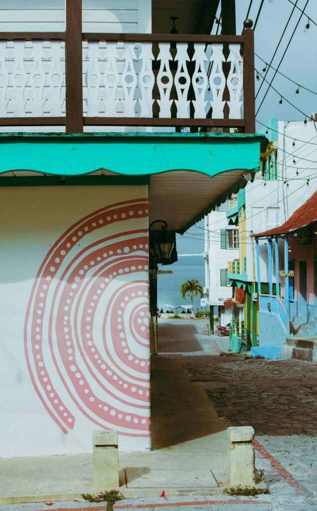 Vibrant street scene with artistic murals and colorful buildings in a tropical setting.