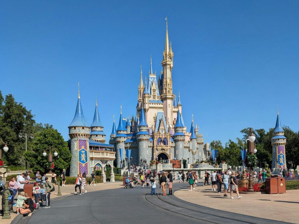 Cinderella Castle at Walt Disney World's Magic Kingdom, Florida, surrounded by visitors on a bright sunny day.