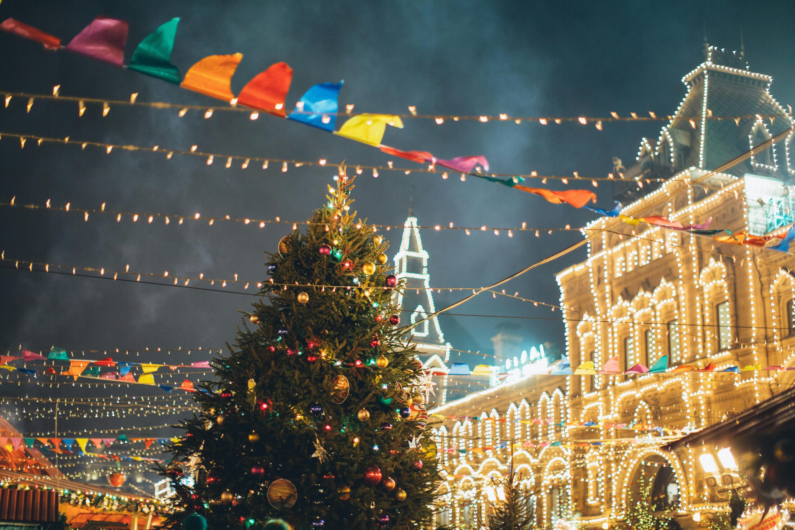 Vibrant Christmas market scene featuring a decorated tree and twinkling lights at night.