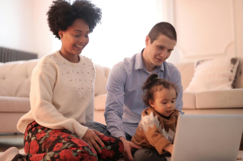 A family enjoying quality time together with a laptop in a cozy living room setting.