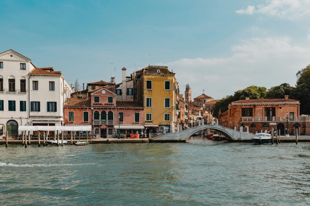 Charming view of Venice's canal with vibrant buildings and a stone bridge under a clear sky.