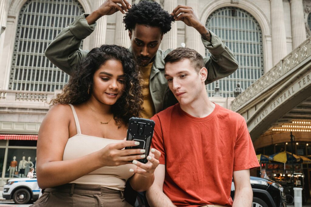 A group of friends bonding and browsing on their phones outside Grand Central Terminal.