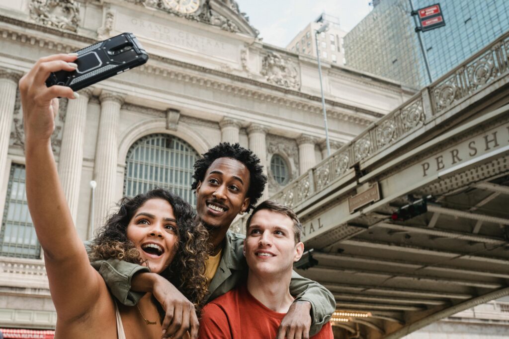 Group of friends capturing a joyful selfie in front of Grand Central Terminal, NYC.