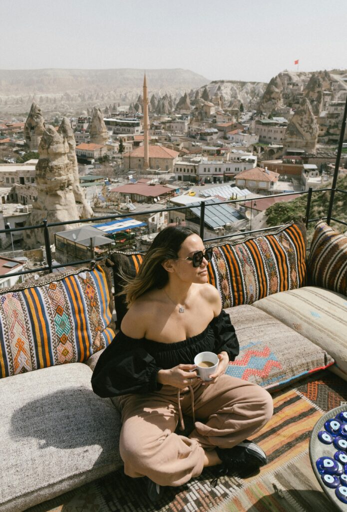 Tourist sipping coffee on a terrace with stunning Cappadocia landscape view.