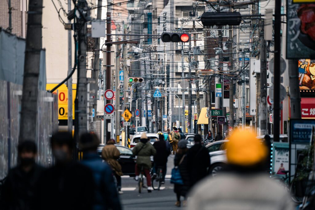 Vibrant street in Osaka, Japan, bustling with people, traffic, and urban signs.