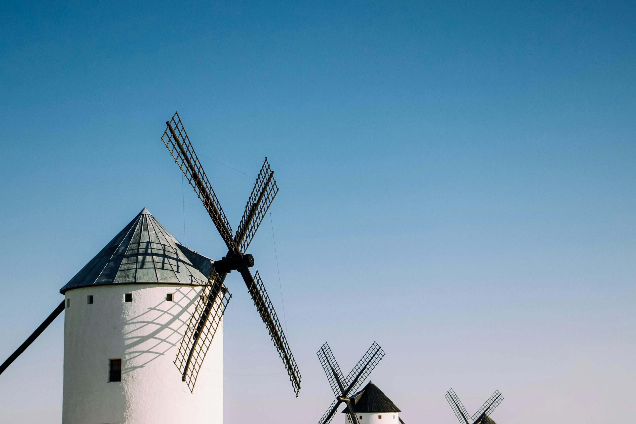Windmills in Castilla-La Mancha, Spain under a clear blue sky, symbolizing renewable energy.