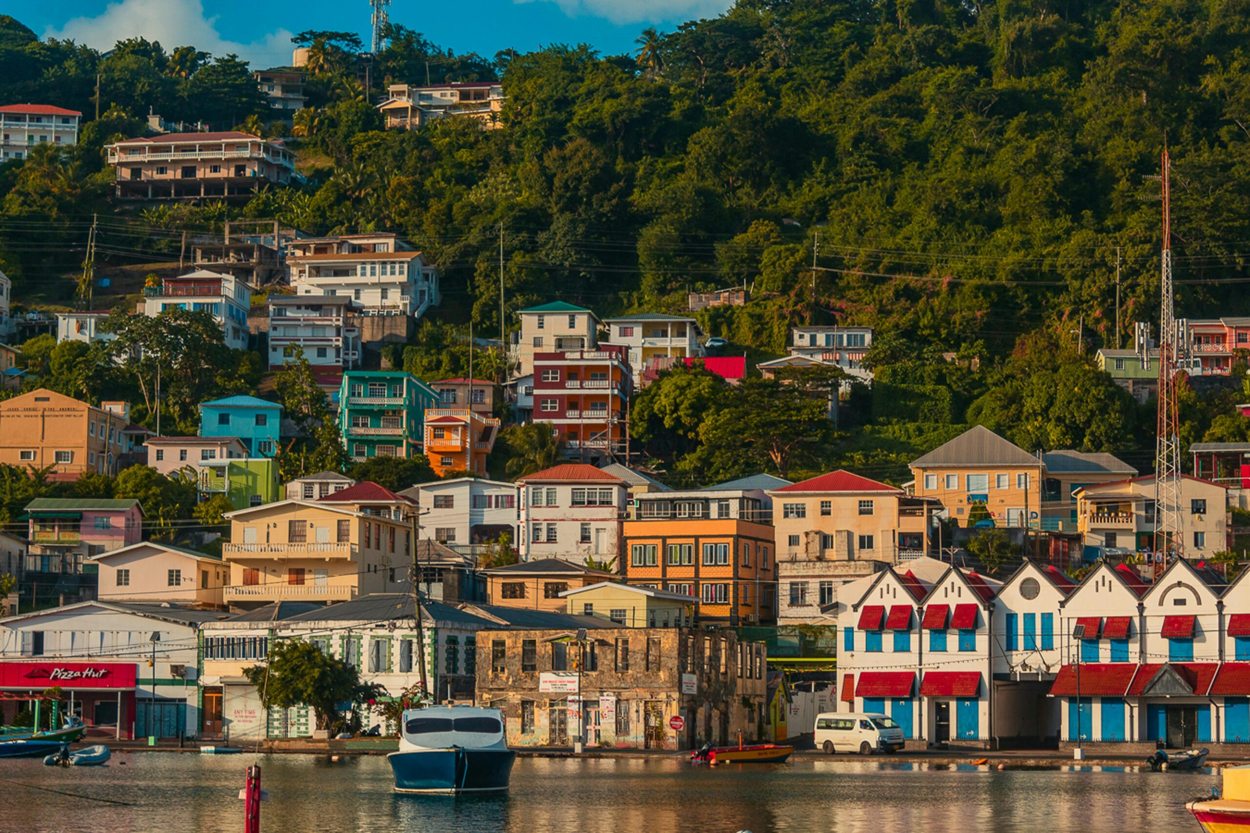 Captivating view of a vibrant hillside town in Grenada, featuring colorful buildings and a calm harbor.