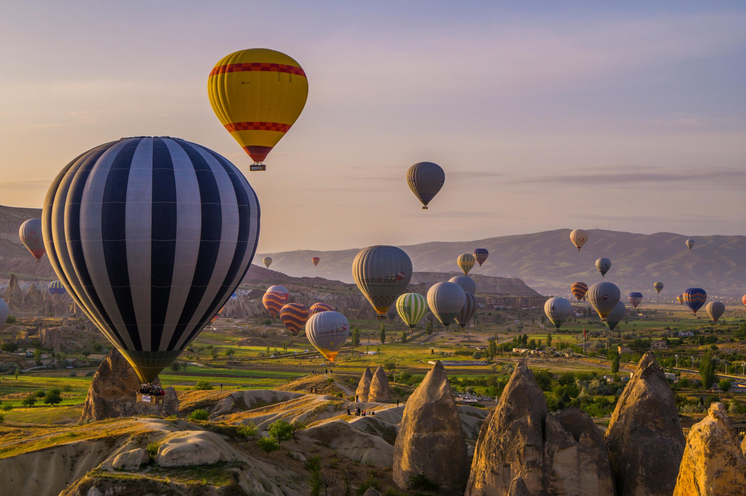 Hot air balloons soar over Cappadocia's unique landscape at sunrise, offering a breathtaking view.