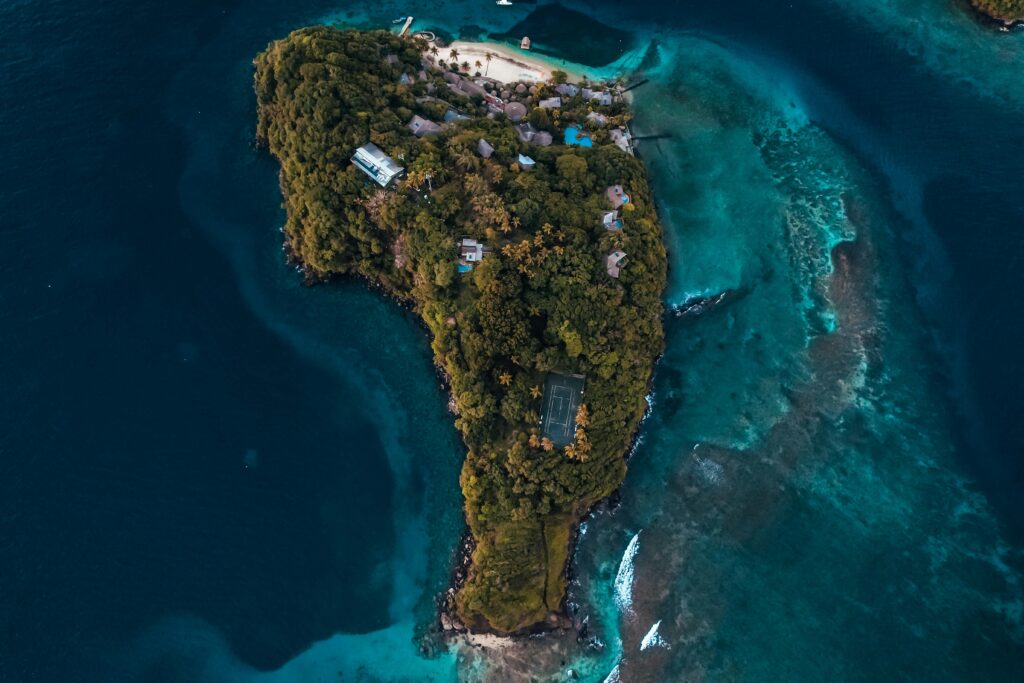 Stunning drone shot capturing a lush tropical island surrounded by vibrant blue sea.