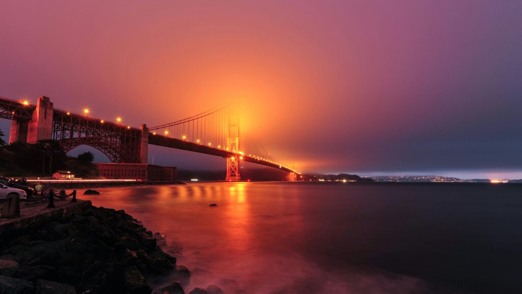 Dramatic view of the Golden Gate Bridge illuminated at twilight as fog rolls in.