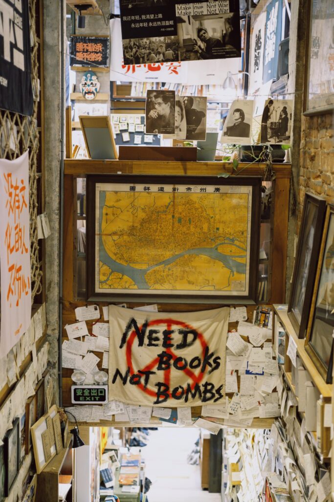 A cozy bookstore interior filled with books, maps, and political posters promoting peace.