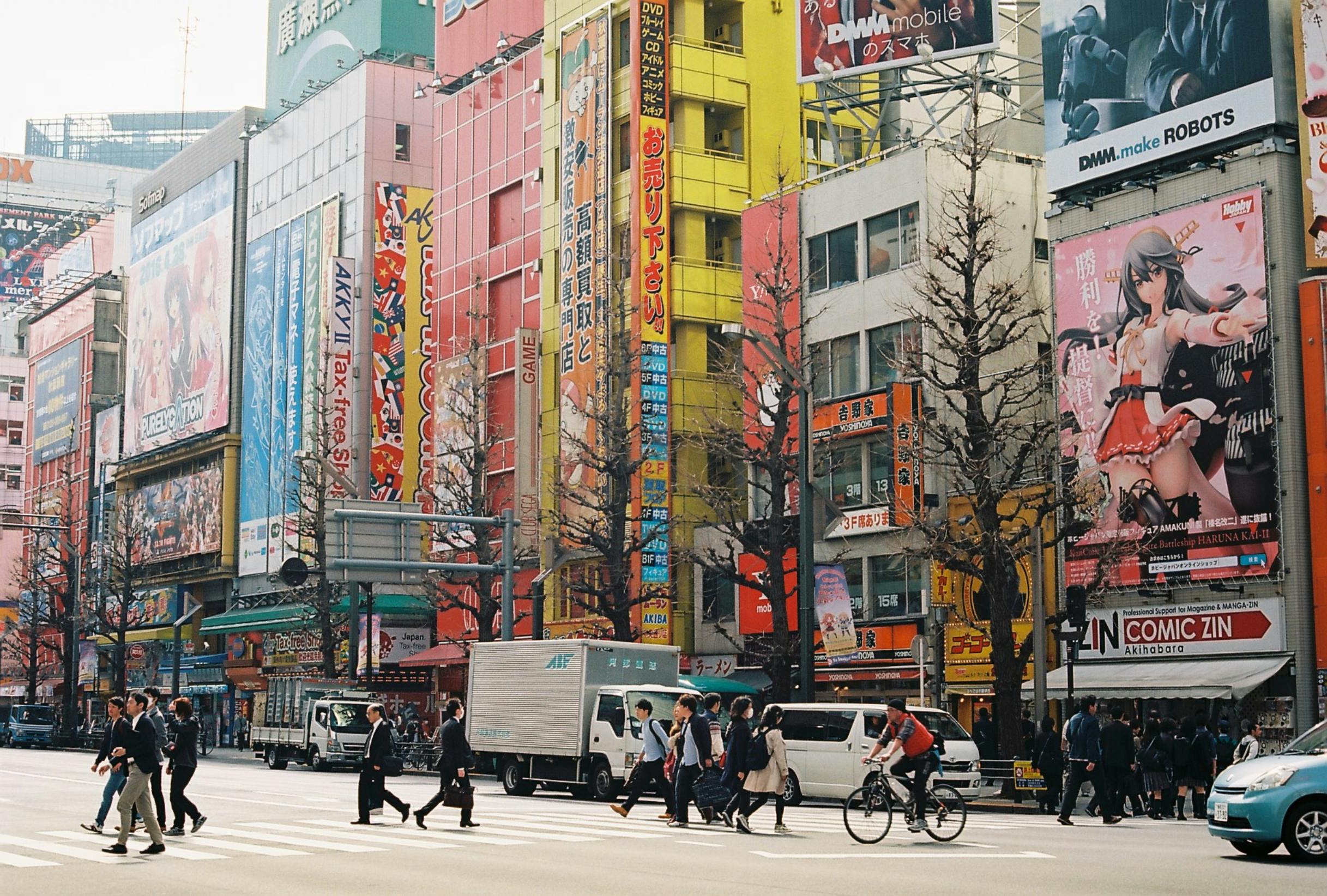 Busy Akihabara street in Tokyo with colorful billboards and pedestrians.