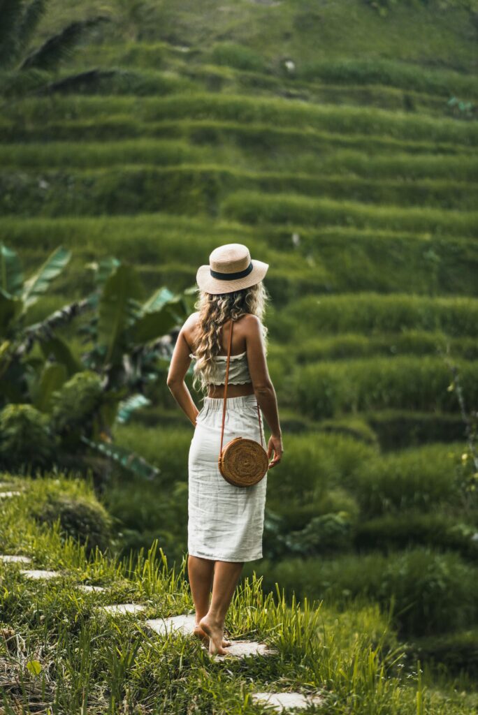 A woman in a hat admires the lush green rice terraces, capturing a serene rural landscape.