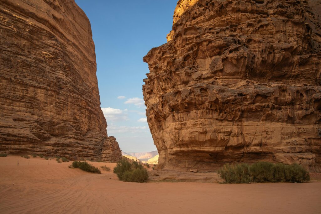 Breathtaking view of Wadi Rum's iconic red sandstone cliffs under a clear sky in the Jordanian desert.
