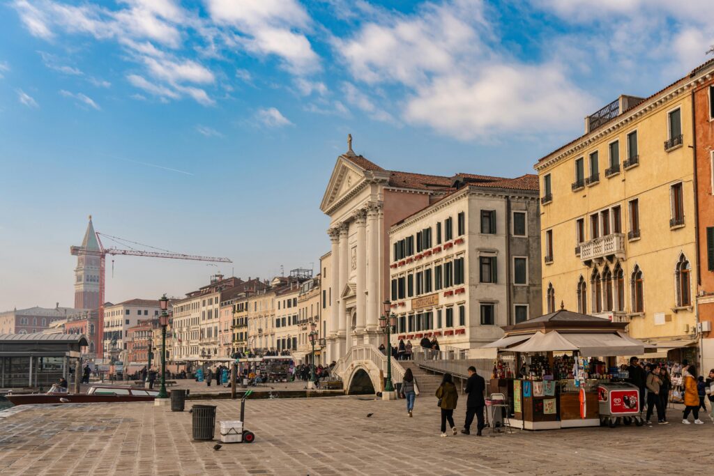 Picturesque street view in Venice showcasing historic architecture and vibrant street life under a blue sky.