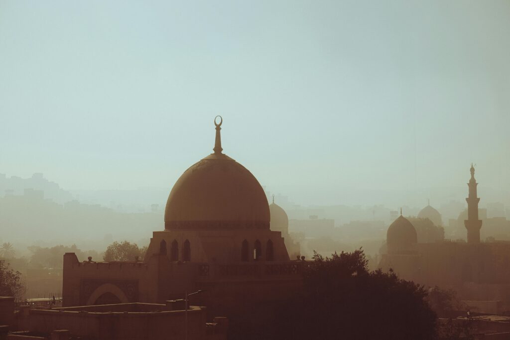 Serene view of Cairo's skyline silhouetted in mist, highlighting ancient Islamic architecture.