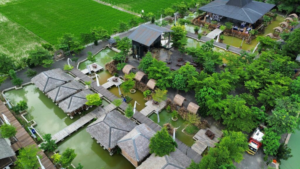 Aerial shot of a peaceful countryside resort with green fields and rustic buildings.