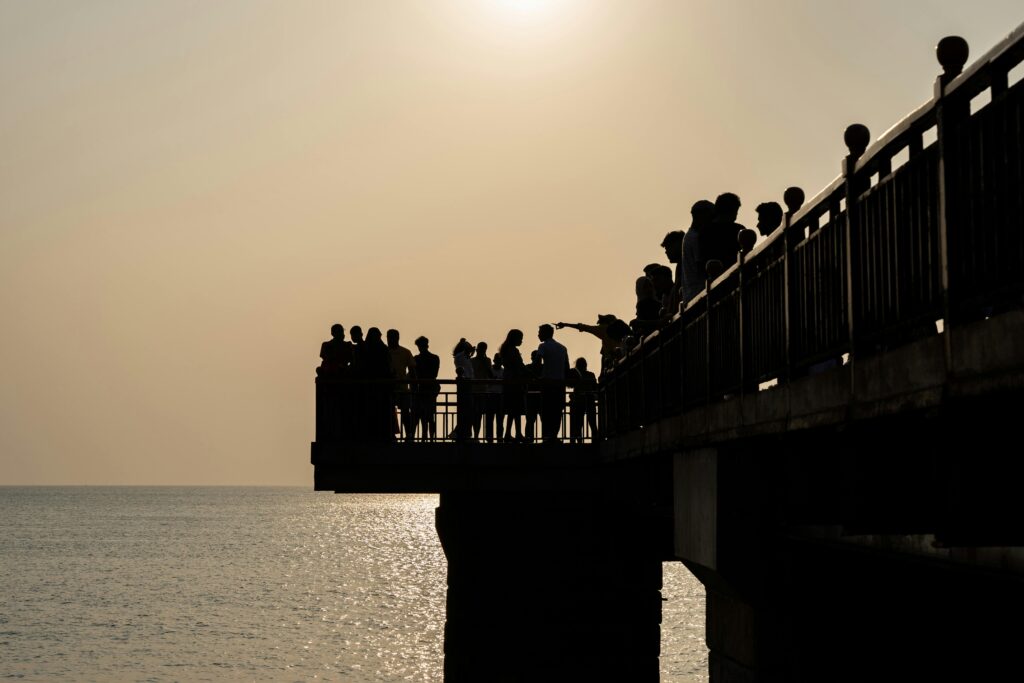 A serene view of people silhouetted against the sun on a pier in Colombo.