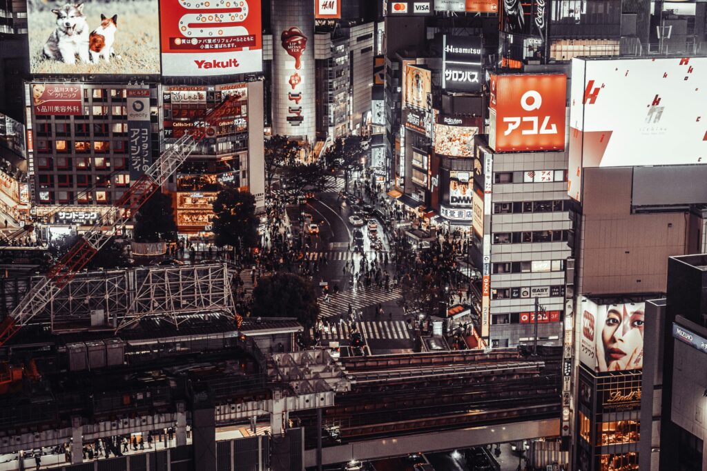 A bustling aerial view of Shibuya Crossing, Tokyo at night, showcasing vibrant city life and illuminated billboards.