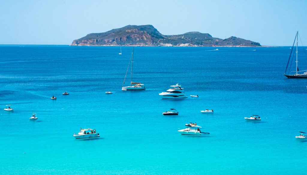 A scenic view of yachts and sailboats in the turquoise sea of Sicily, Italy.