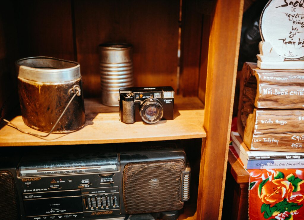 A vintage camera and assorted items on a wooden shelf in a cozy setting.