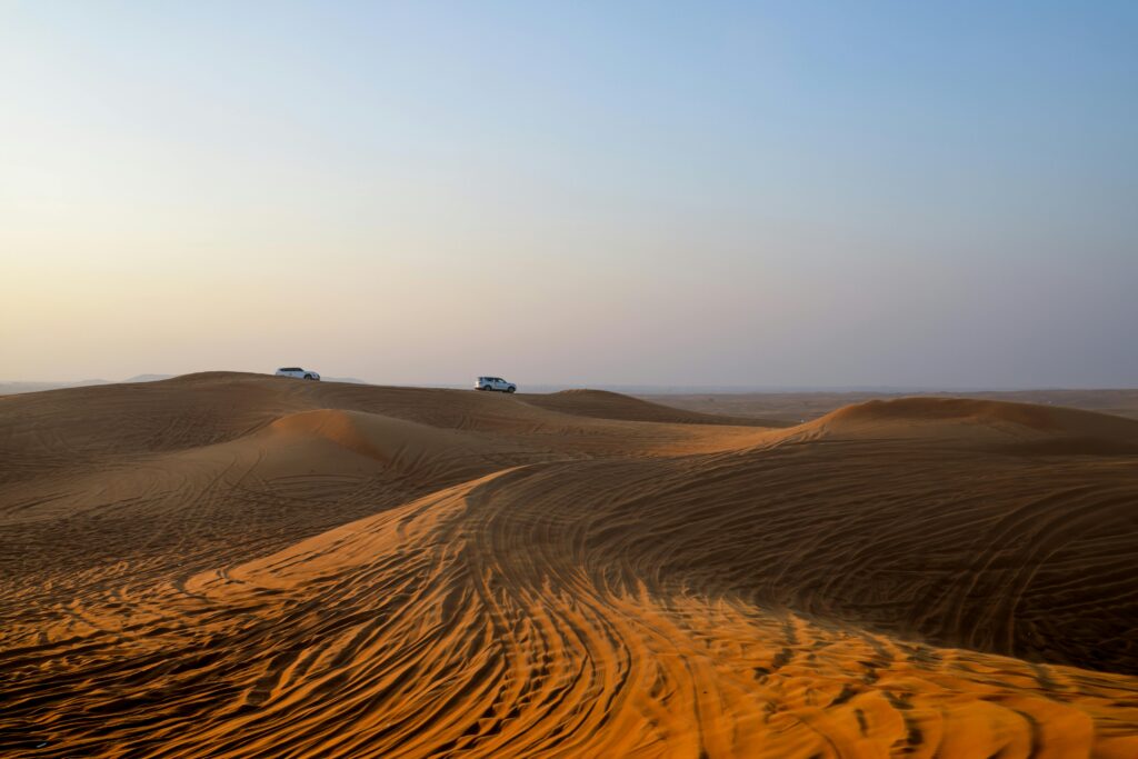 Traversing the serene desert dunes by car, capturing the essence of a desert safari at dawn.
