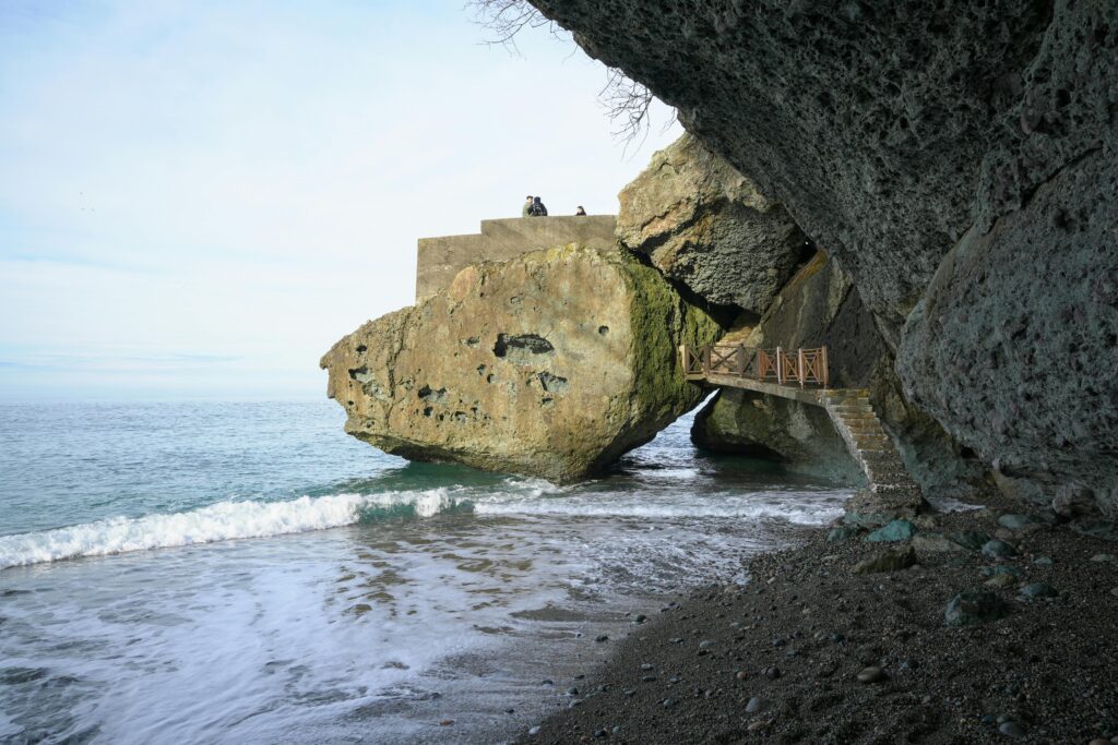 Dramatic rock formation by the sea with a scenic walkway, perfect for travel exploration.