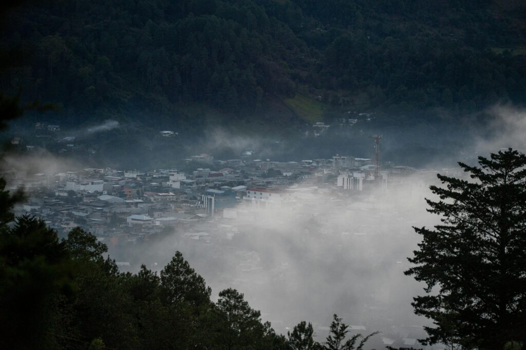 Fog drifts over the town of Quiché in the highlands of Guatemala, creating a serene and mysterious landscape.
