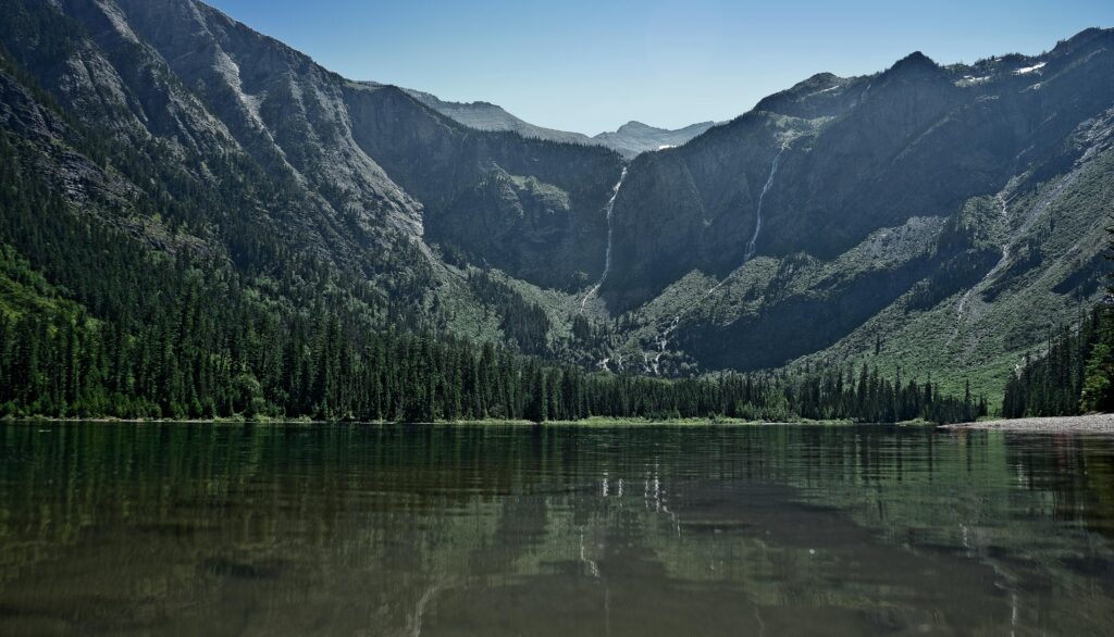 Stunning landscape of Avalanche Lake with mountain reflections and lush greenery in Montana.