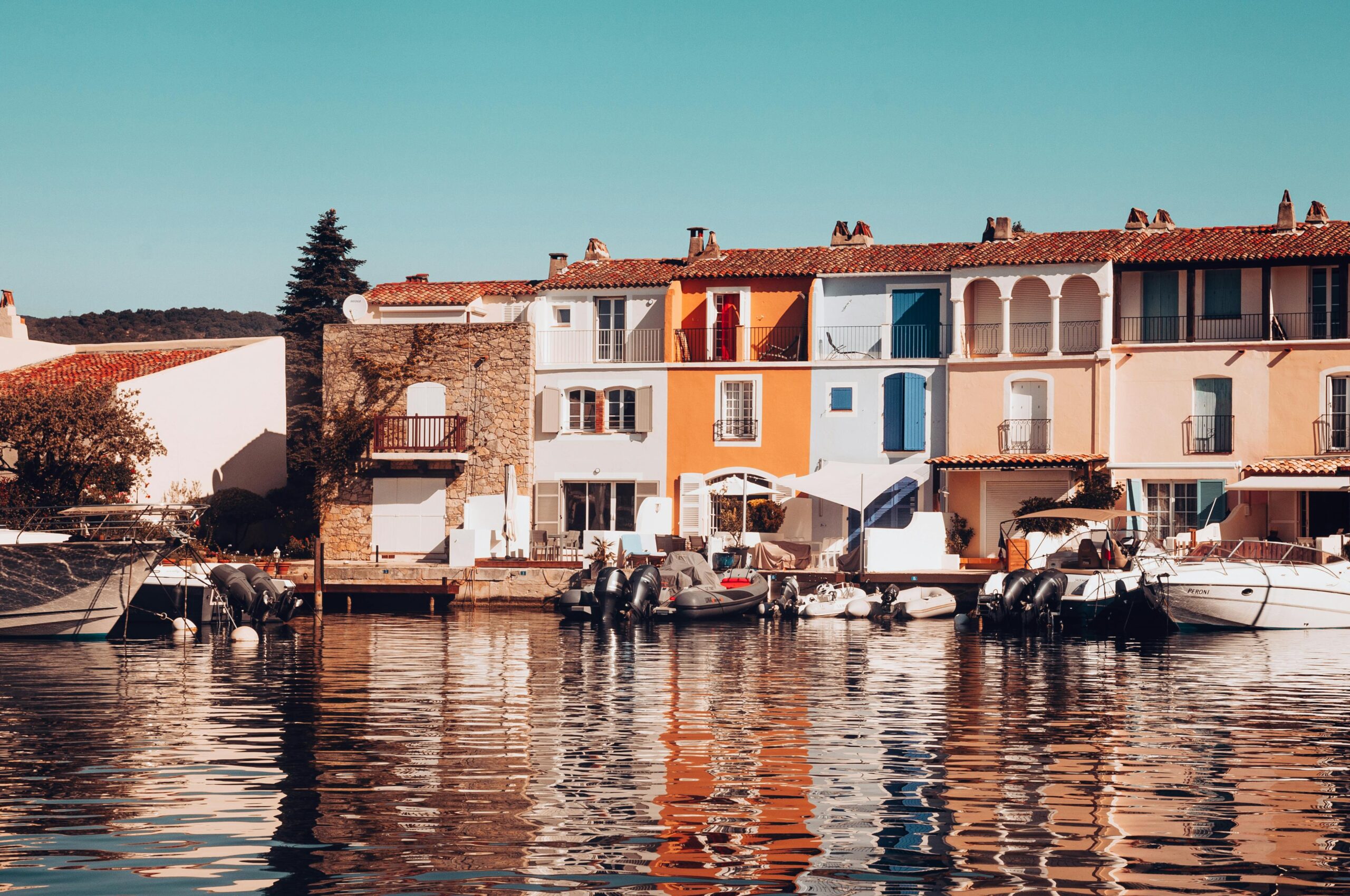 Colorful waterfront houses and boats at Grimaud, France, under bright daylight.