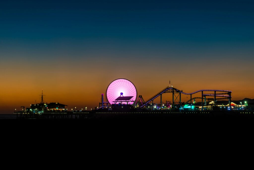 Vibrant view of Santa Monica Pier featuring a glowing Ferris wheel at sunset, capturing the lively atmosphere.