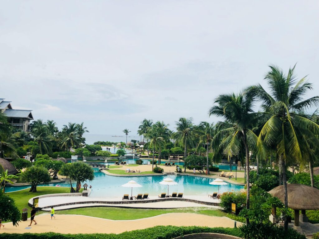 A stunning view of a tropical resort pool surrounded by palm trees in Sanya, Hainan, China.