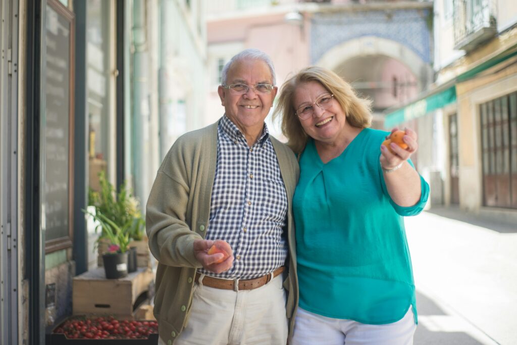 Smiling senior couple enjoying a day out shopping in a sunny Portuguese street.