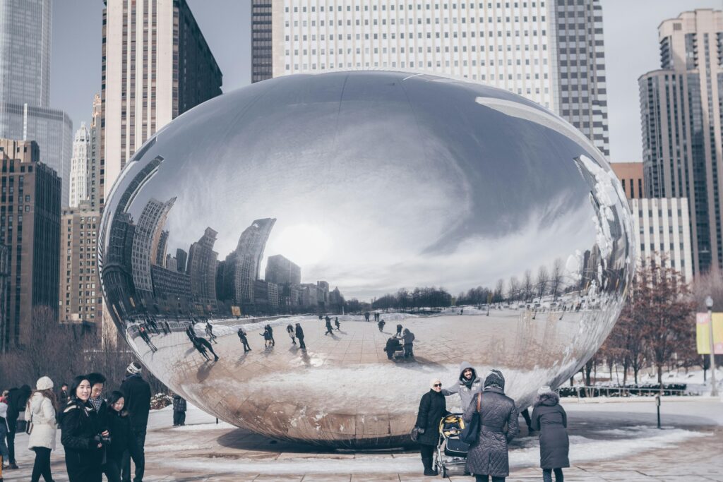 Iconic Cloud Gate in Chicago reflecting cityscape and people on a winter day.