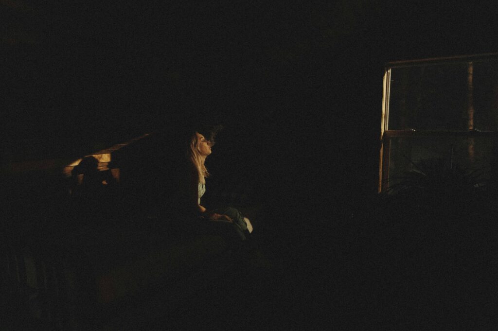 Silhouette of a woman sitting by a window at night, creating a mysterious ambiance.