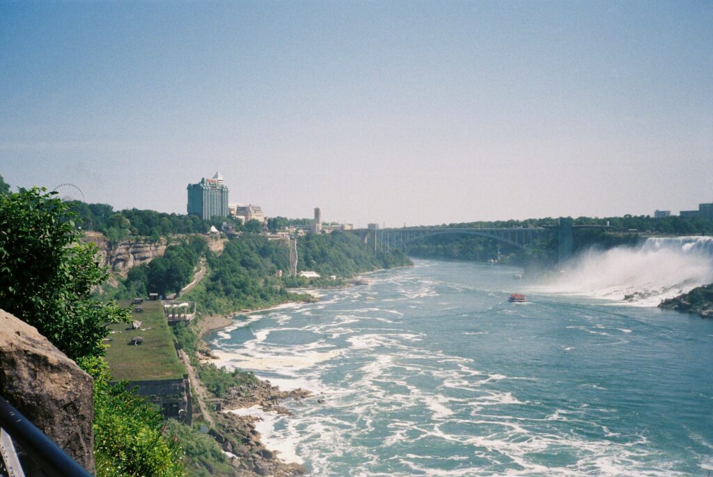 Stunning view of the Niagara River with waterfalls and a bridge under a clear sky.