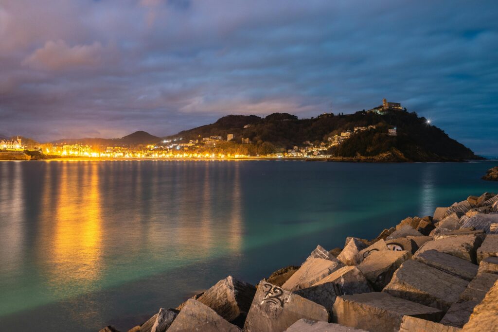 Capture of San Sebastian's coastline at night, showcasing shimmering lights and a serene seascape.