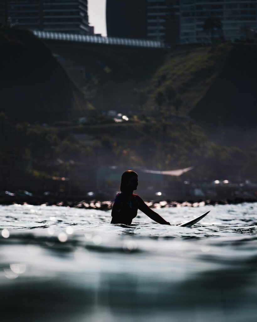 Silhouette of a surfer against an urban backdrop in stunning evening light.