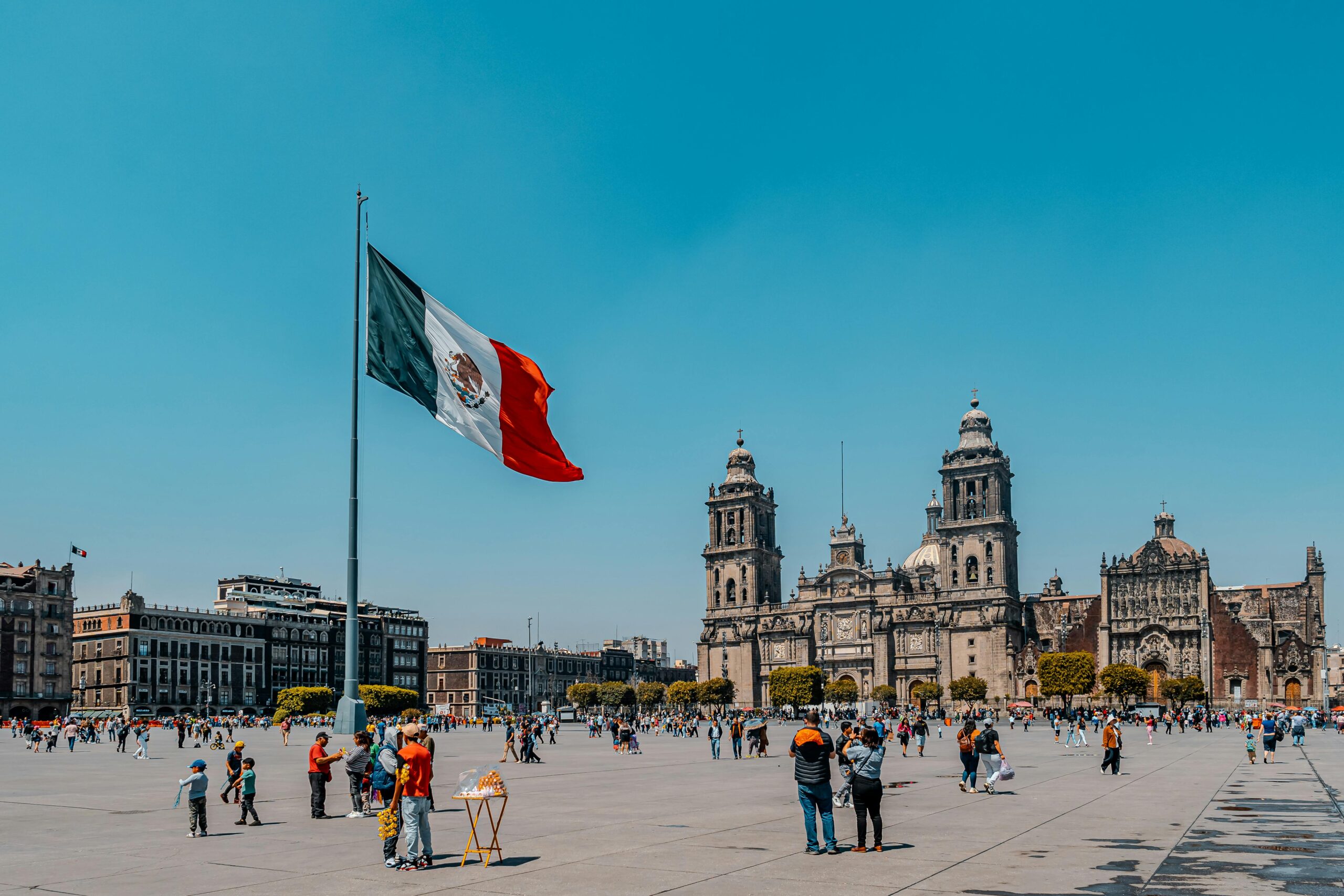 Vibrant view of Mexico City's Metropolitan Cathedral and Plaza de la Constitución under a clear blue sky.