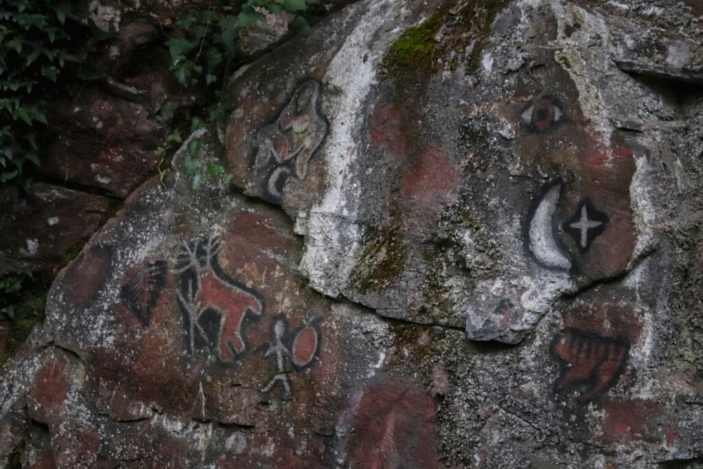 Detailed view of prehistoric art and petroglyphs on a rugged rock surface, showcasing ancient history.