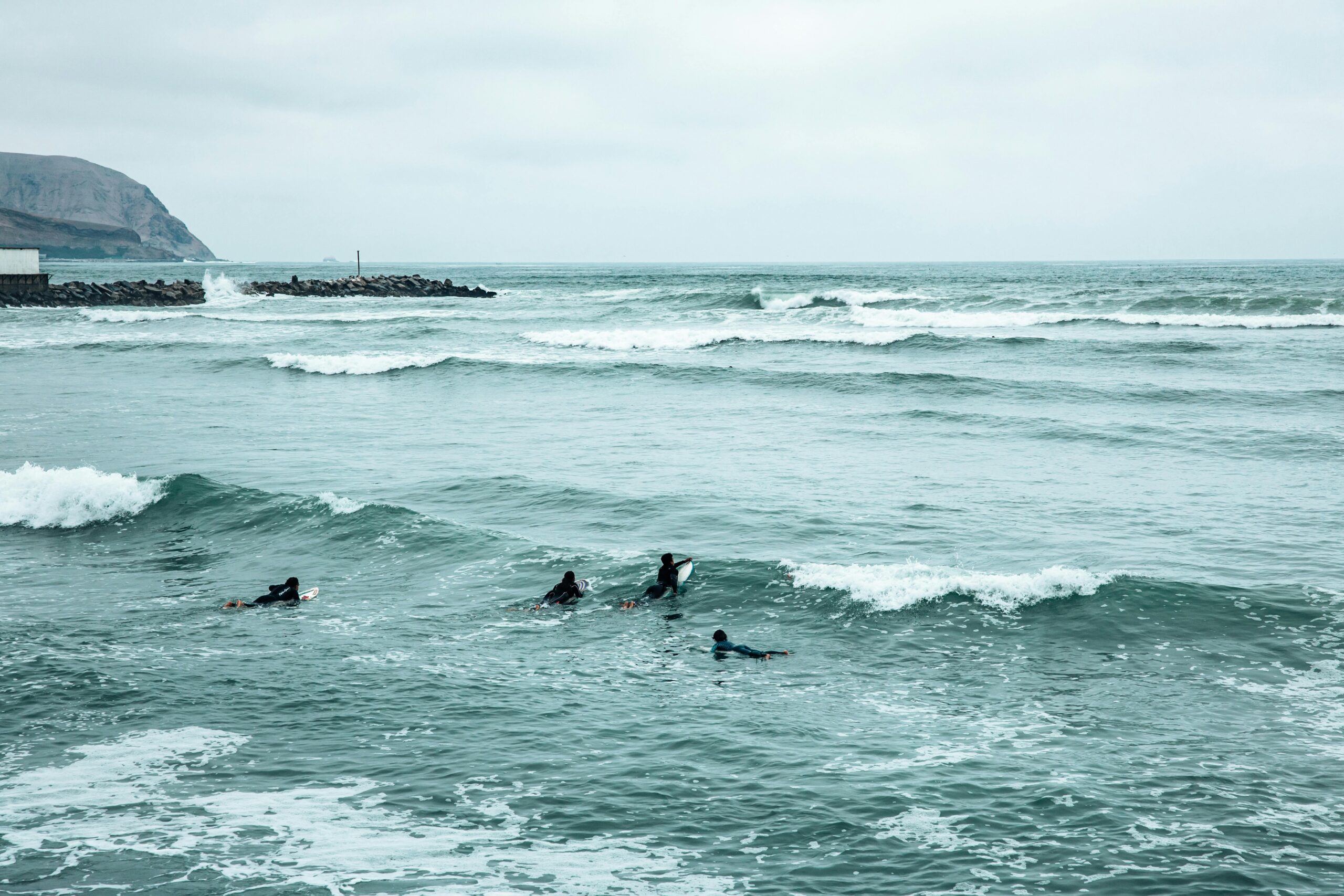 Group of surfers navigating waves off the coast of Lima, Peru, showcasing the vibrant surfing culture.