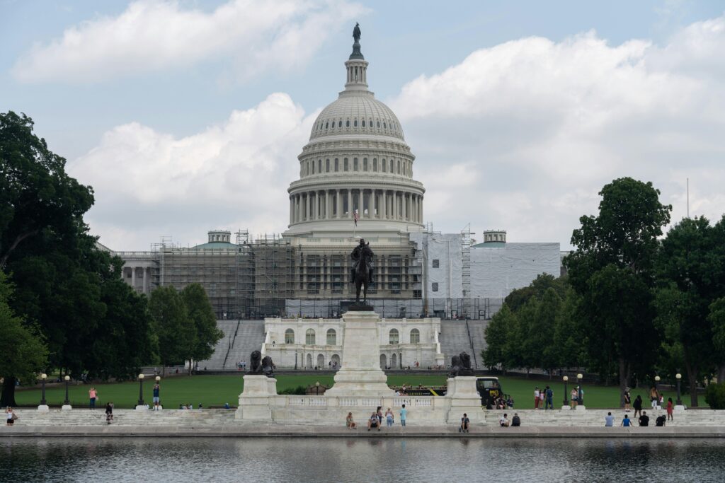 US Capitol with dome, statue, and reflecting pool on a sunny day in Washington, D.C.
