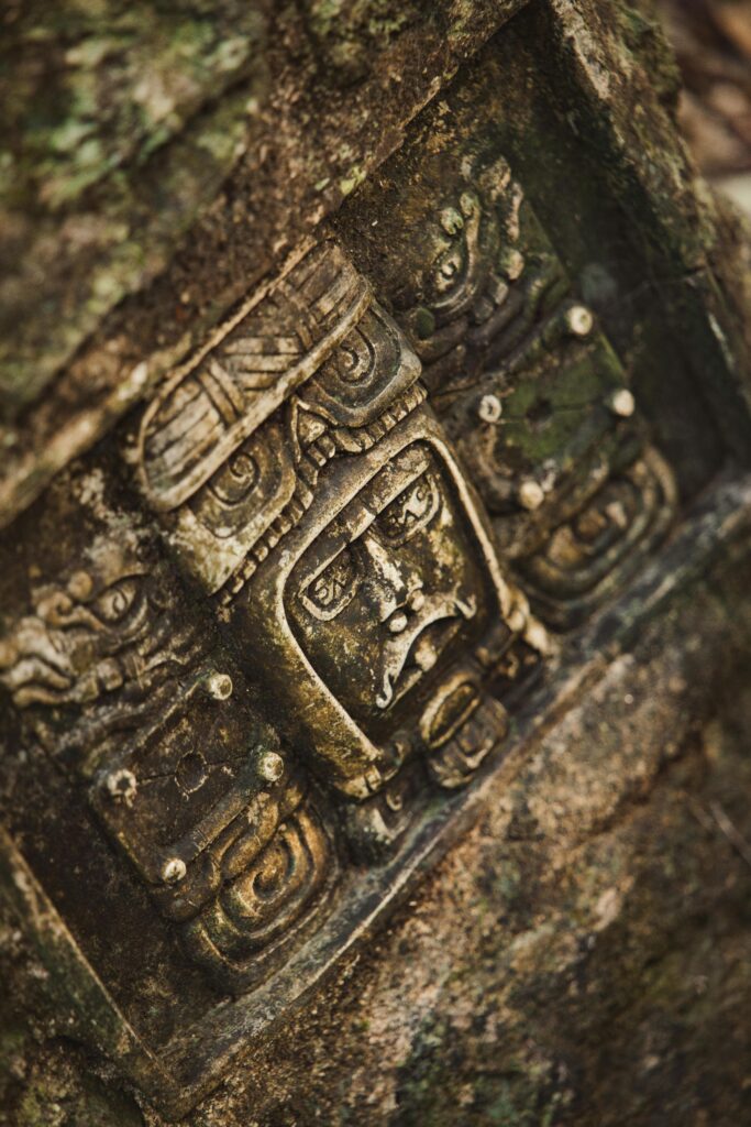 Close-up of a detailed ancient Mayan carving on a weathered stone surface.