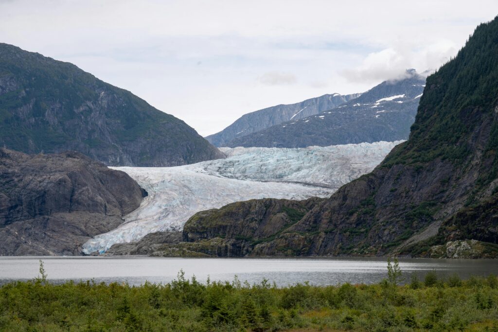 A scenic view of Mendenhall Glacier and lake in Juneau, Alaska surrounded by mountains.