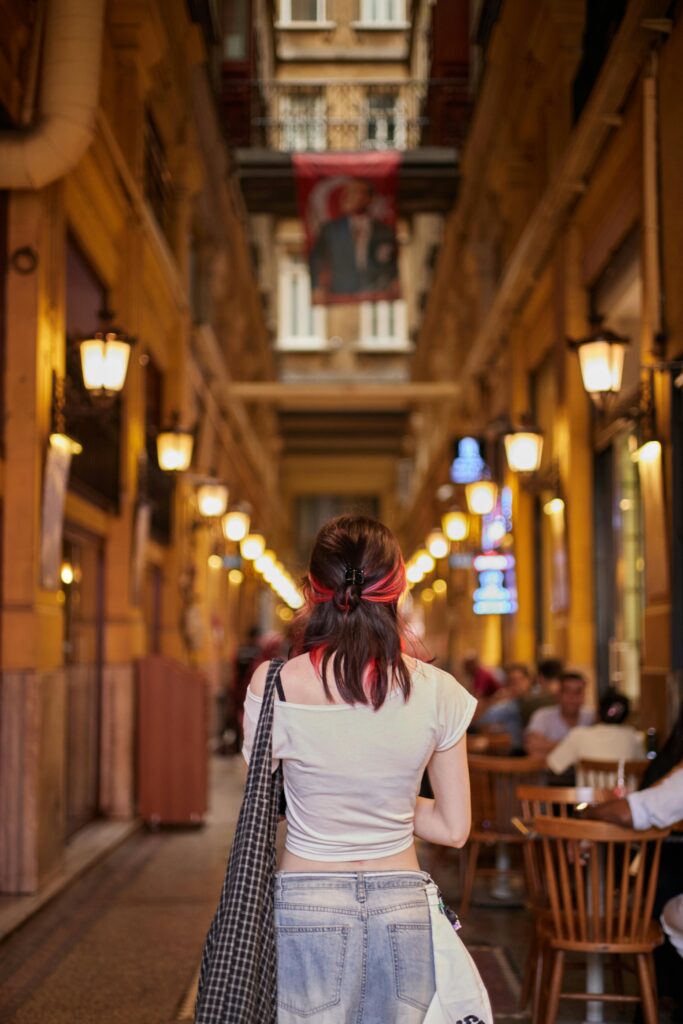 A young woman strolls through a charming lit passageway in Istanbul, Türkiye.